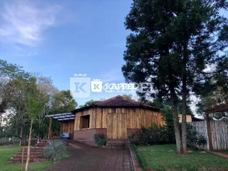 Fachada de uma casa de madeira com degraus e vegetação ao redor.