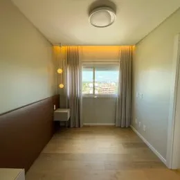 Hall de entrada com piso de madeira e cortinas.