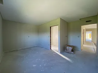 Ambiente interno de uma sala ampla com piso de concreto e paredes claras.
