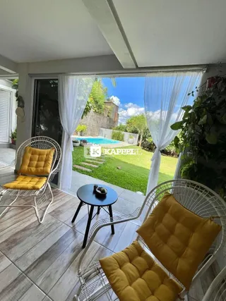 Área externa com móveis de vime e vista para a piscina.
