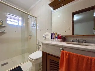 Foto de um banheiro com box de vidro e azulejos brancos.