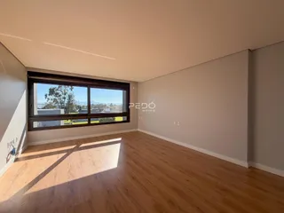 Sala de estar com piso de madeira e grande janela de vista para o exterior.