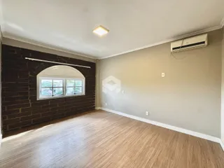 A sala apresenta uma parede de tijolos escuros e piso de madeira clara.