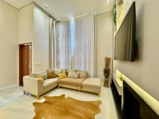 Sala de estar com sofá claro e cortinas brancas.