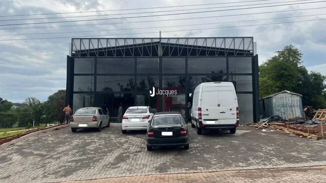 Fachada moderna de um edifício comercial em Lajeado, Brasil, com veículos estacionados na frente.