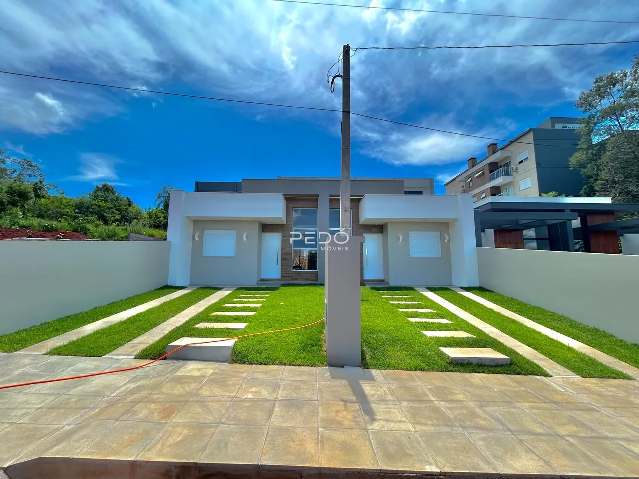 Fachada de uma casa moderna em Lajeado, Brasil, com jardim e muro branco.