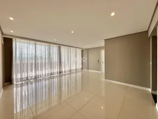 Ambiente interno amplo com piso de porcelanato claro e cortinas brancas.