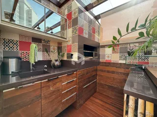 Vista da cozinha com armários de madeira e revestimento colorido.