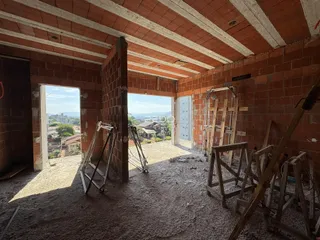 Interior de uma construção com paredes de tijolo aparente e teto de concreto.