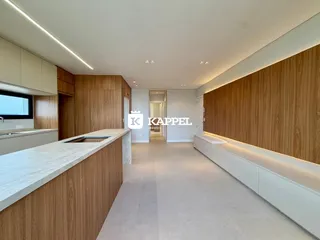 Vista de uma cozinha moderna com ilha e armários de madeira em um ambiente claro.
