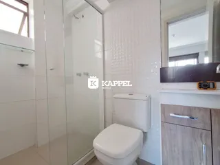 Banheiro com box de vidro e vaso sanitário branco.