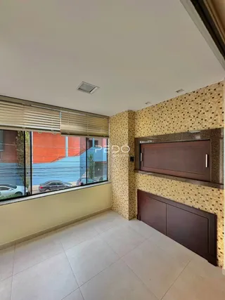 Sala de estar com piso claro e grandes janelas que dão vista para o exterior.