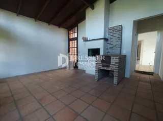 Interior de uma sala com piso de cerâmica e parede de tijolos aparentes.
