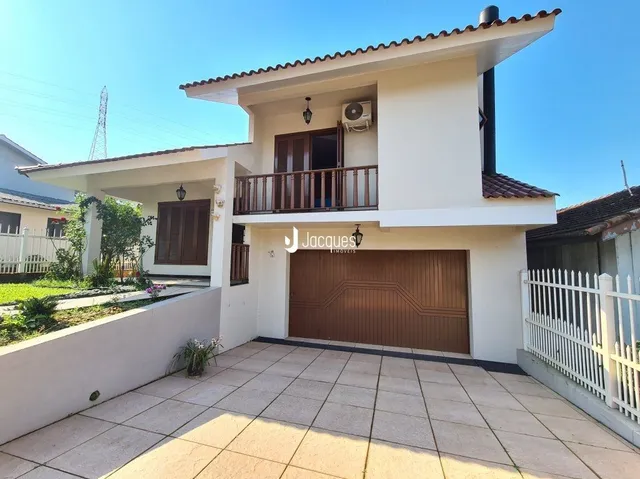 Fachada de uma casa em Lajeado, Brasil com garagem e cerca branca.