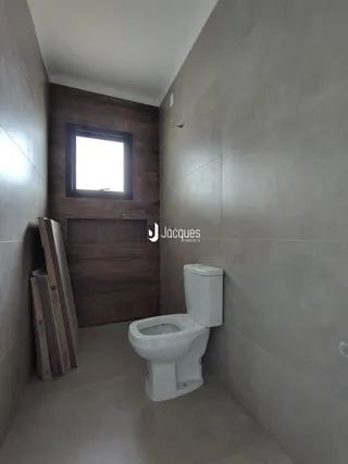 Foto de um banheiro interno com parede de madeira e janela.