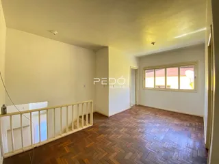 Hall de entrada com piso de madeira e grade de segurança em imóvel no Brasil.