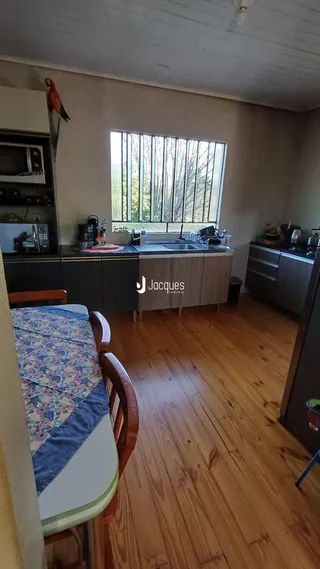 Interior da cozinha com piso de madeira e janela.
