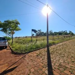 Vista externa de uma área gramada e estrada de terra sob um céu azul.