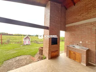 Área externa com paredes de tijolos aparentes e vista para um campo gramado.