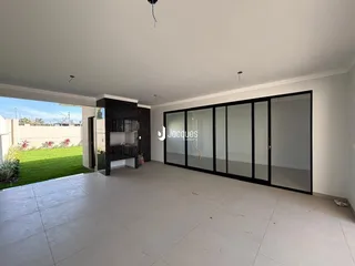 Vista interna de uma área ampla com portas de vidro que se abrem para um jardim.