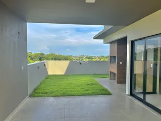 Vista externa de um pátio com gramado verde e muro branco.