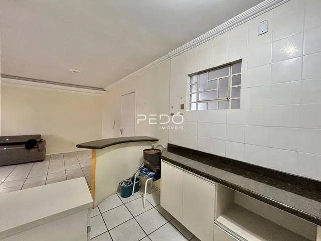 Imagem de uma cozinha com revestimento de cerâmica e armários brancos.