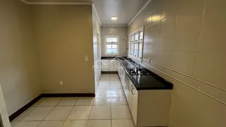 Vista de uma cozinha com bancada escura e piso claro em um imóvel em Lajeado.