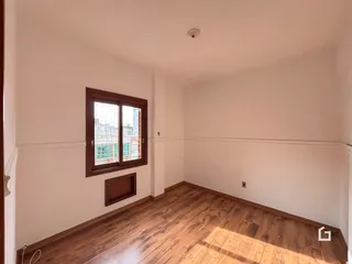 Ambiente interno com piso de madeira e parede branca.