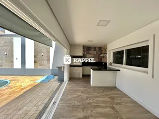 Vista do ambiente interno com cozinha e acesso a uma área externa com piscina.