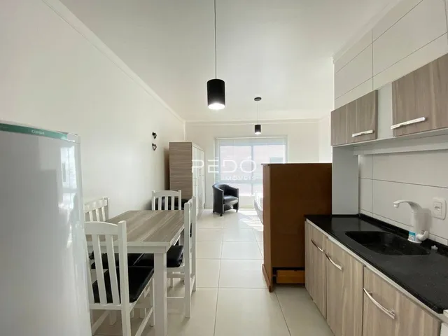 Ambiente interno de uma sala de jantar e cozinha com piso de cerâmica.