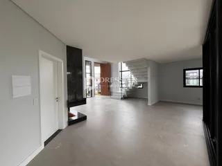 Interior de uma sala de estar ampla com piso de concreto polido e paredes brancas.