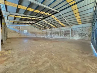 Espaço industrial interno com piso de concreto e paredes de tijolo.