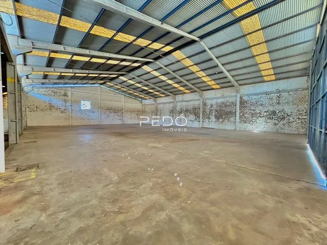 Espaço industrial interno com piso de concreto e paredes de tijolo.