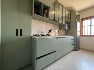 Cozinha moderna com armários verdes e bancadas brancas.
