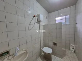 A foto mostra o interior de um banheiro revestido com azulejos brancos.
