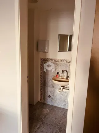 Banheiro com revestimento cerâmico e pia.