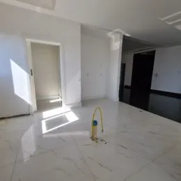 Sala de estar com piso de mármore claro e paredes brancas.
