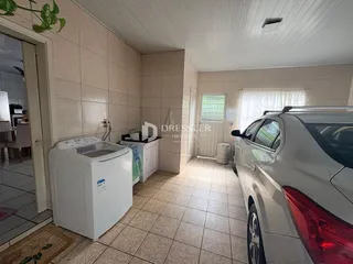 Interior de uma área com piso de cerâmica e máquina de lavar roupa.