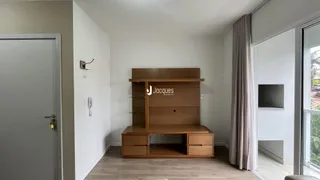 Uma sala de estar com paredes brancas e piso de madeira clara.