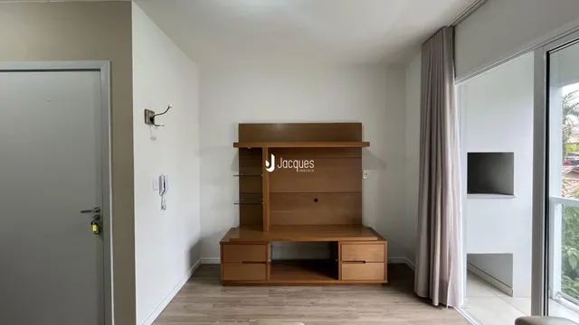 Uma sala de estar com paredes brancas e piso de madeira clara.
