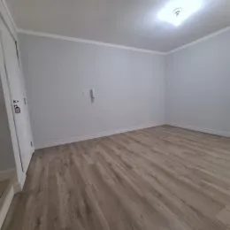 Foto de um cômodo interno com piso de madeira clara e paredes brancas.