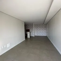 Foto de um corredor interno com paredes brancas e piso cinza.