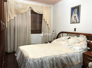 Quarto com cama e cortinas claras em ambiente interno.