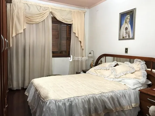 Quarto com cama e cortinas claras em ambiente interno.
