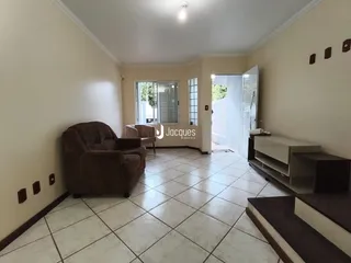 A sala de estar possui piso de cerâmica claro e um sofá marrom.