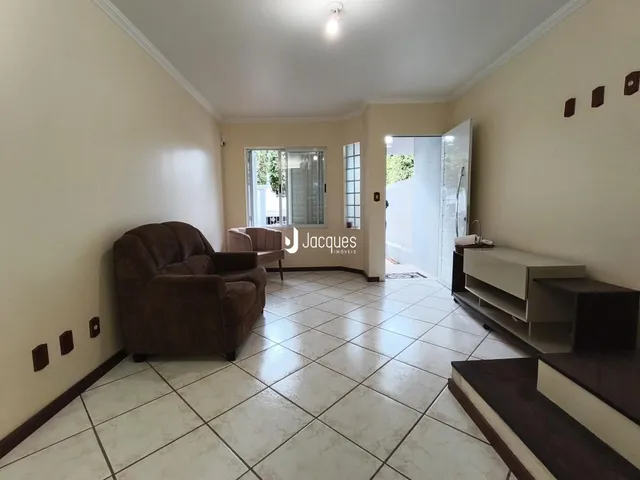 A sala de estar possui piso de cerâmica claro e um sofá marrom.