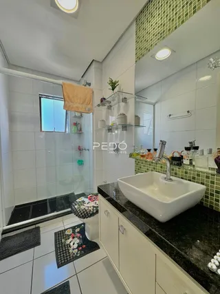 Foto do interior de um banheiro com box de vidro e bancada escura.