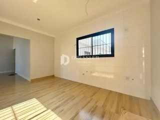Ambiente interno com piso de madeira clara e parede branca.