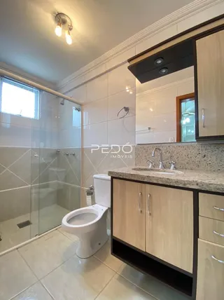 Foto de um banheiro com revestimento cerâmico e box de vidro.