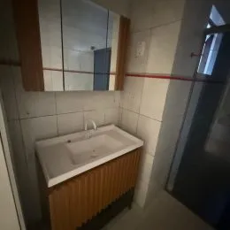 Foto de um banheiro com bancada e revestimento de azulejos brancos.